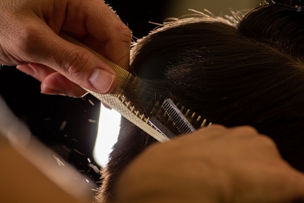 Stylist trimming hair with comb and shears